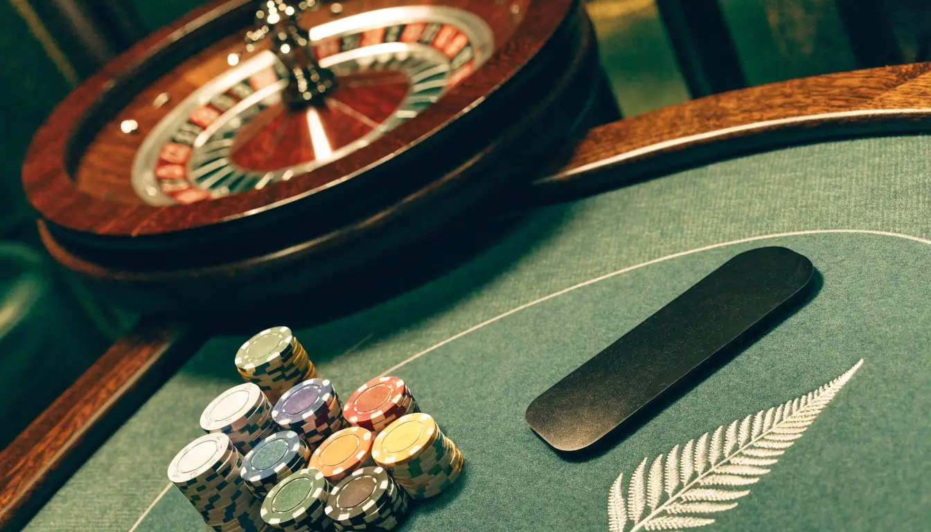 Casino chips, roulette wheel and Prezzy Card on a wooden New Zealand themed gaming table.